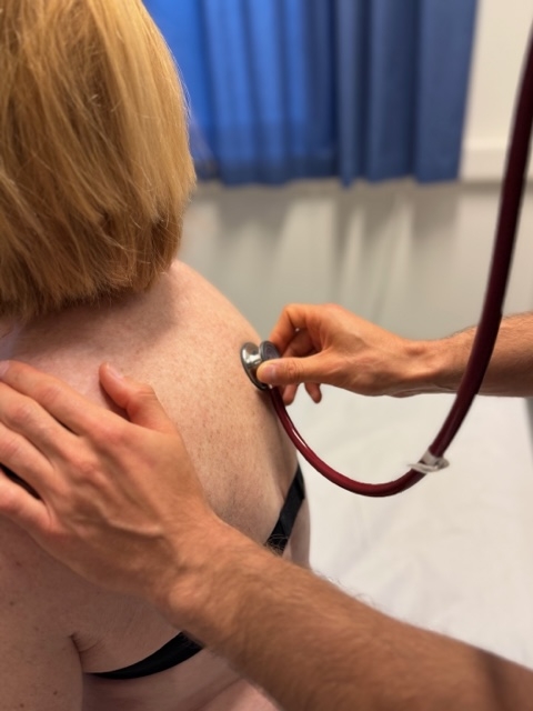 Läkare lyssnar på patients hjärta i ett stetoskop.